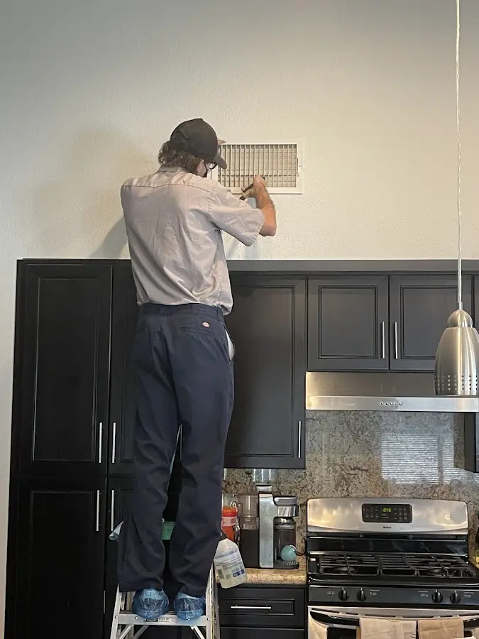 Technician inspecting an air vent during HVAC service in Anacortes
